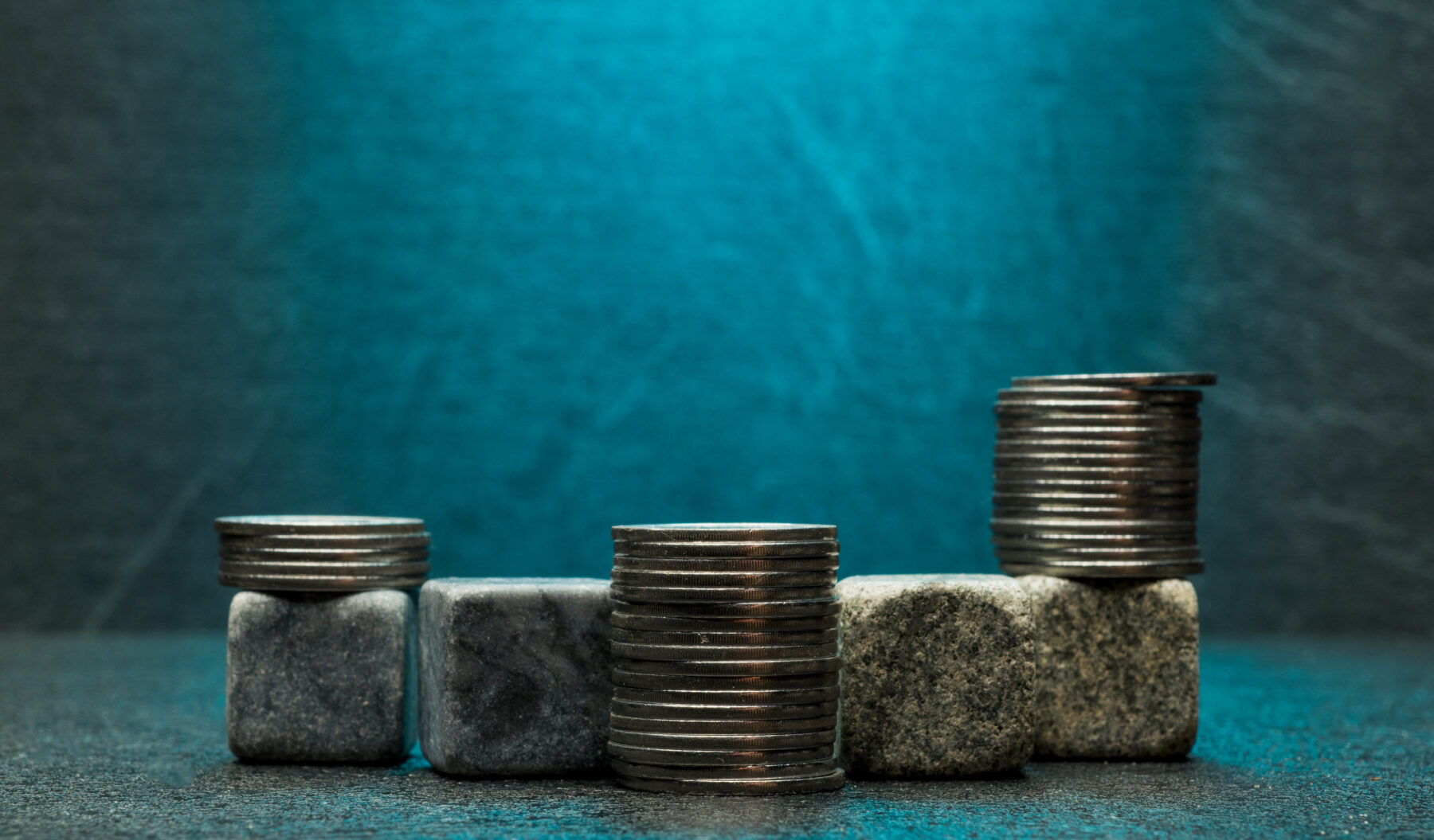 Stacks of coins on construction materials illustrating how material choices impact construction project budgets