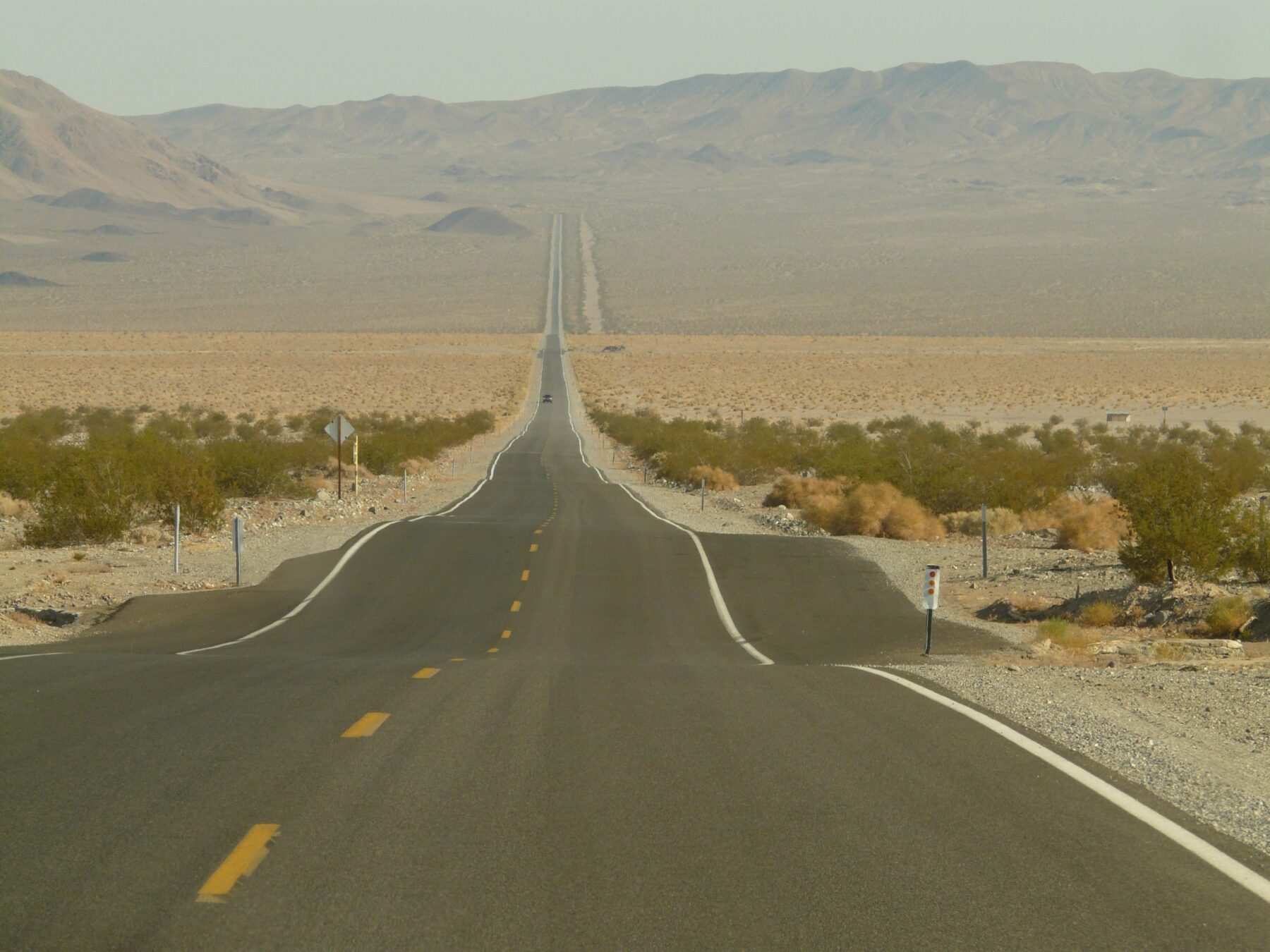 Asphalt road in sunny conditions showing how heat and traffic impact commercial parking lot performance